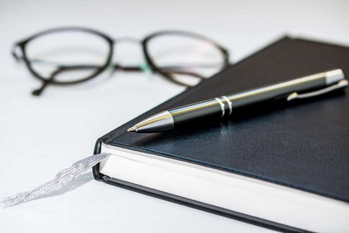 Notebook with pen and reading glasses