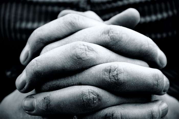 Close-up of intertwined hands in black and white 4K