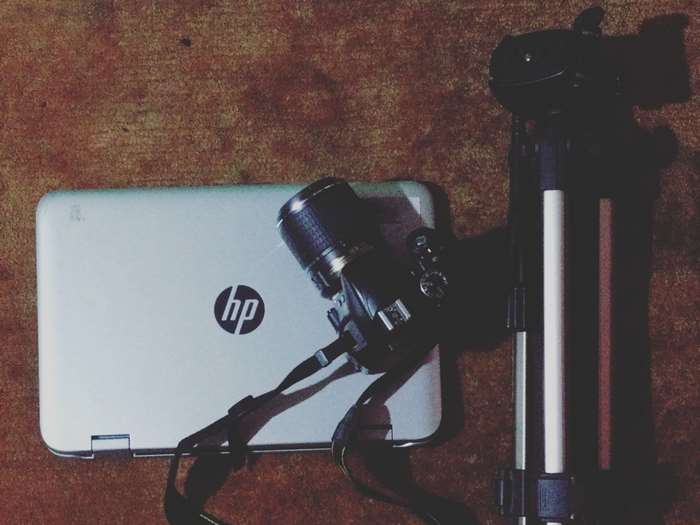 HP laptop, camera, and tripod on a textured surface