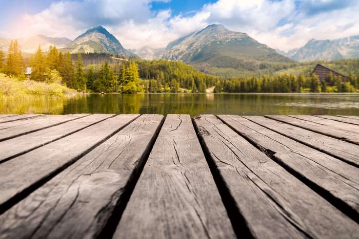 Wooden dock on a tranquil lake with mountains and forest