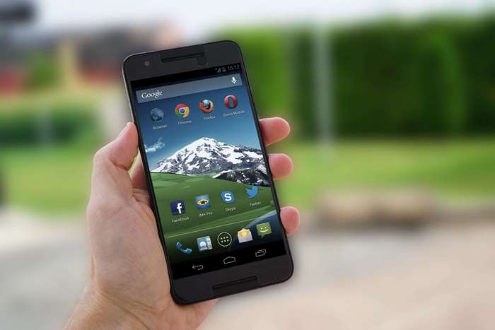 Hand holding a smartphone with apps displayed