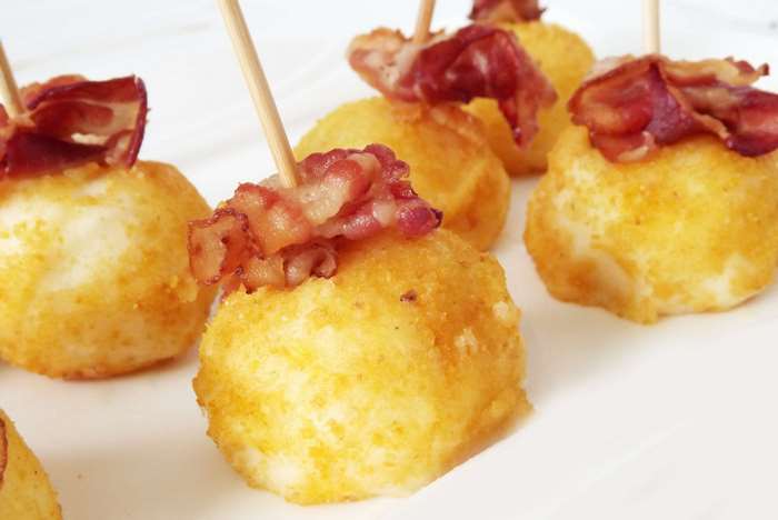 Fried potato croquettes with bacon on toothpicks