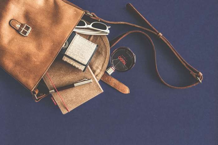 Brown leather bag with wallet, pen, sunglasses, and perfume
