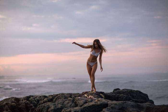 Girl in lingerie on rocks by the ocean 4K