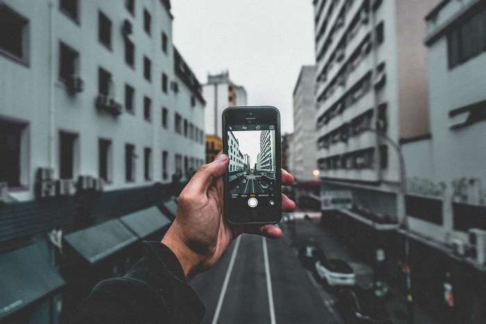 Hand holding iPhone taking picture of city street