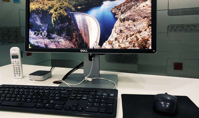 Dell monitor with dam wallpaper, keyboard, mouse, and phone