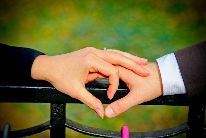 Couple's hands forming a heart shape with engagement ring