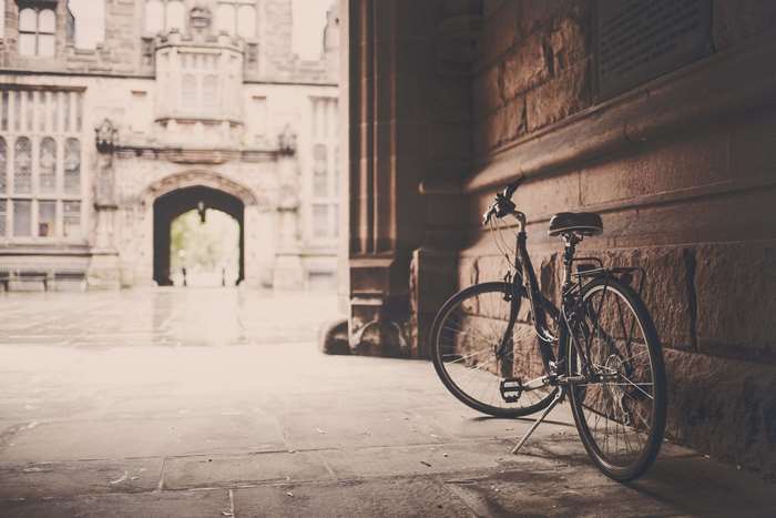 Bicycle leaning against a stone wall near an archway