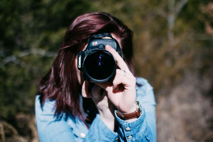 Woman with Canon camera taking a photo outdoors