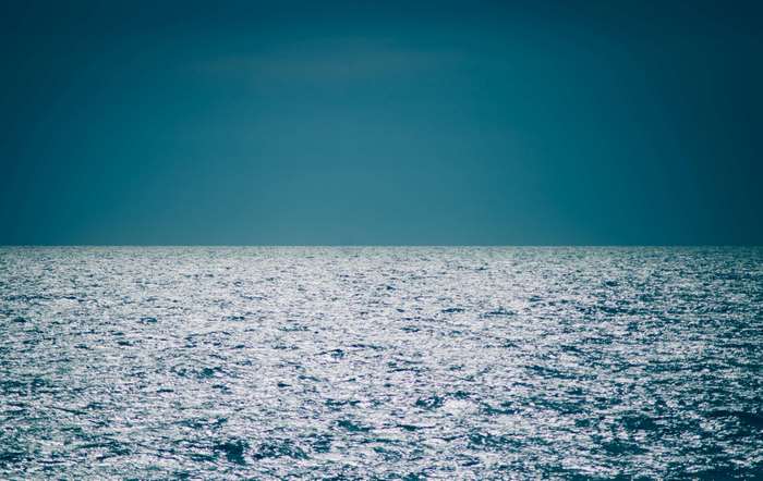 Ocean horizon with sparkling waves under a dark blue sky