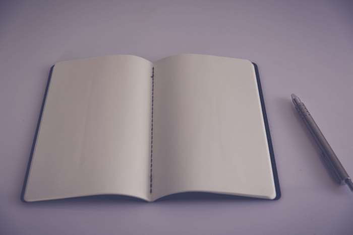 Open notebook with blank pages and a pen