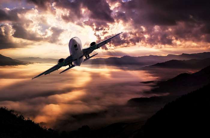 Airplane flying over mountains at sunset 4K