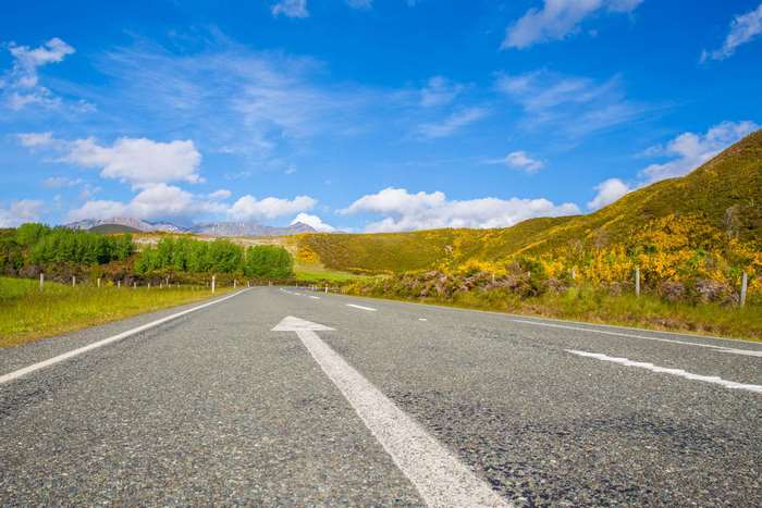 Road with arrow through rolling hills and mountains