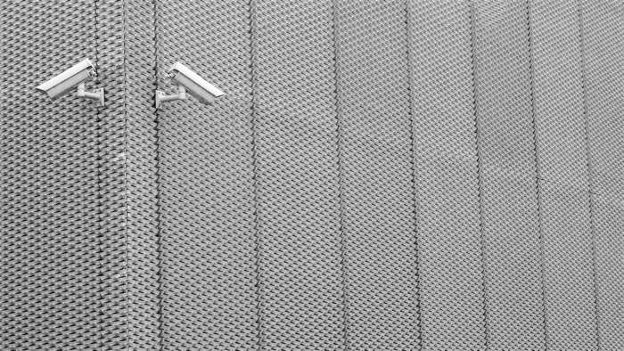 Two security cameras on a textured metal wall