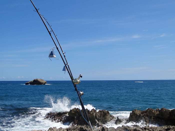 Fishing rod on rocky shore with ocean waves