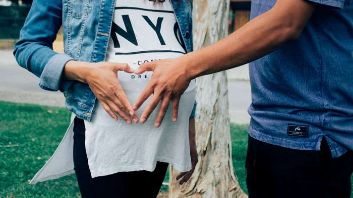 Couple forming heart shape on pregnant belly
