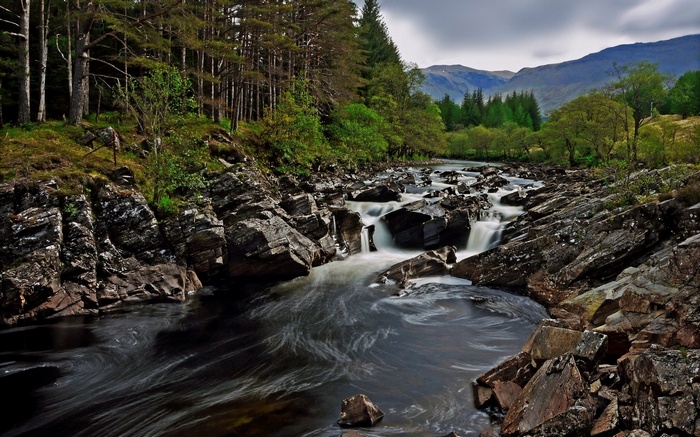 River flowing through rocky terrain with trees and mountains