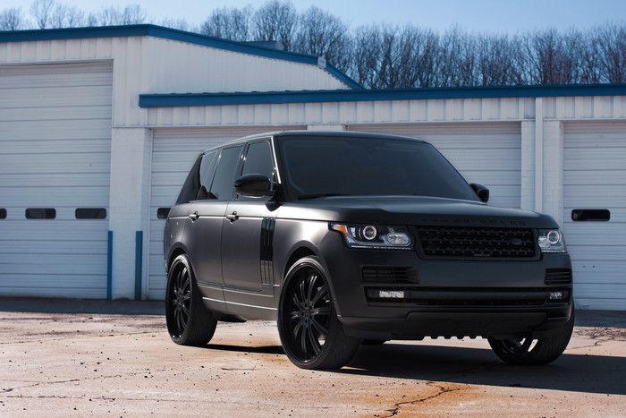Matte black Range Rover parked in front of garages