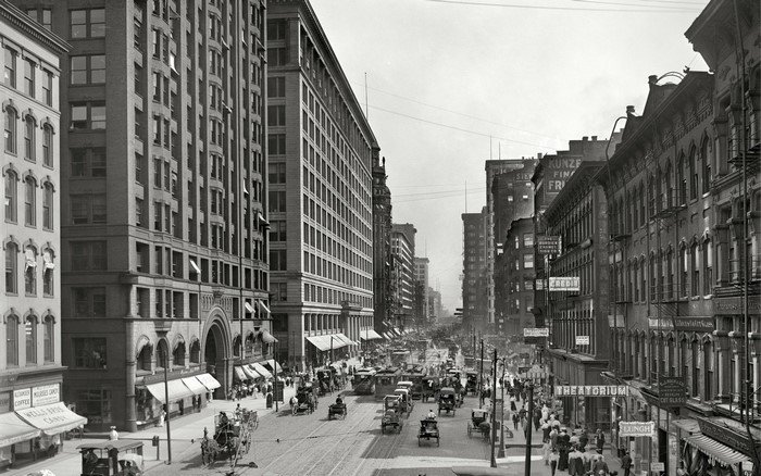 Busy city street with horse-drawn carriages and pedestrians