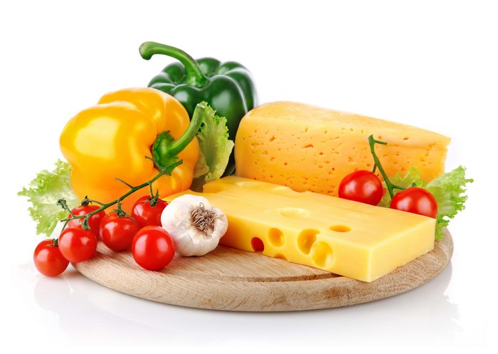 Cheese, vegetables, and tomatoes on a wooden board