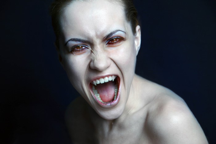 Vampire woman with fangs on black background