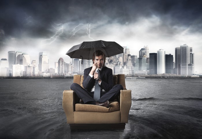 Businessman with umbrella in a flooded city during a storm