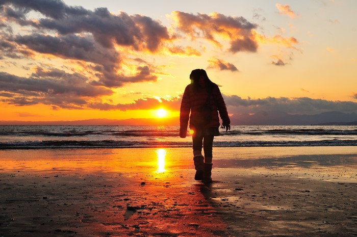 Person walking on a beach at sunset