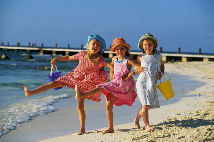 Three girls with buckets on a beach