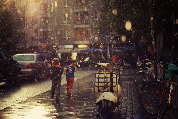 Children running in the rain on a city street