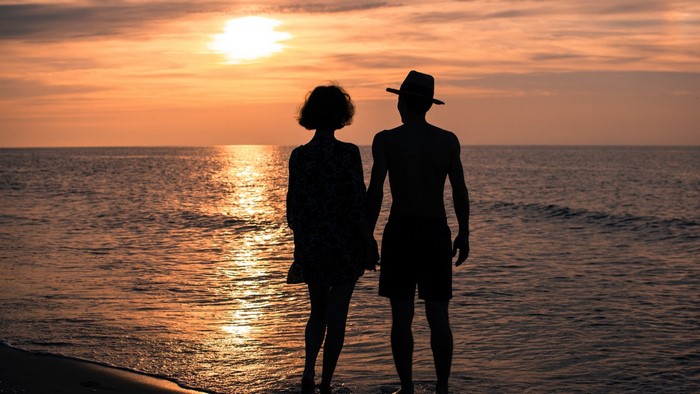 Couple holding hands at sunset on the sea