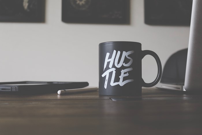 Black mug with "Hustle" inscription on a desk