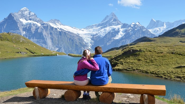 Couple sitting on a bench overlooking a mountain lake