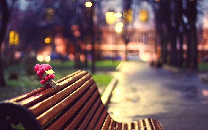 Cardboard robot with pink scarf and hat on bench