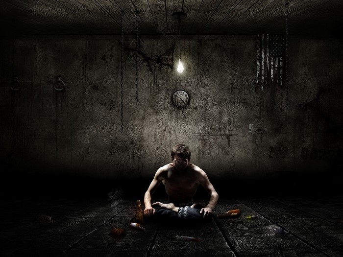 Man meditating in a dark, derelict room