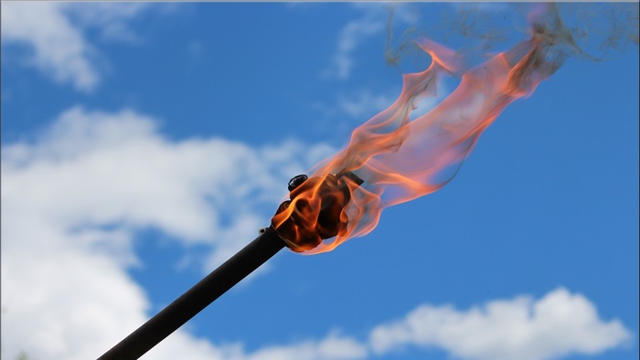 Torch with flame against blue sky
