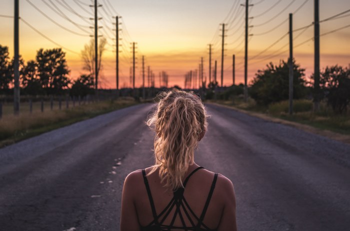 Woman running on road at sunrise