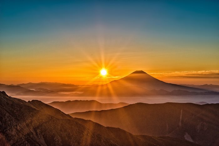 Mount Fuji sunrise over mountains with sun rays