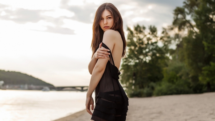 Woman in black dress on a beach at sunset