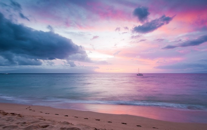 Beach sunset with sailboat and colorful clouds