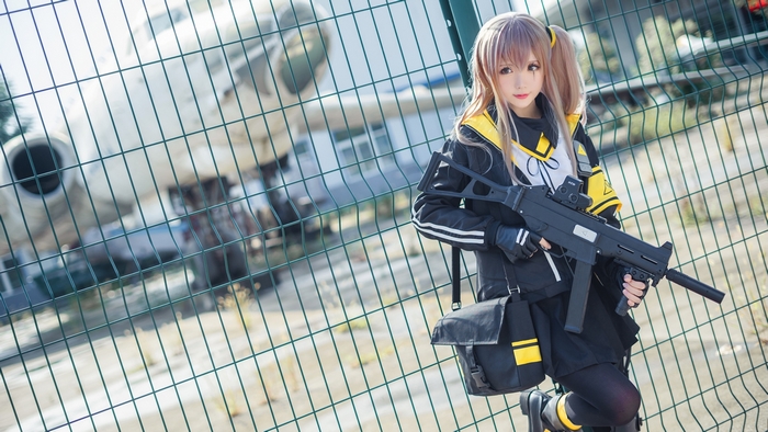 UMP9 Cosplayer holding a submachine gun in front of a fence and airplane