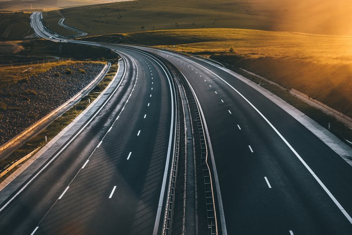 Highway curving through rolling hills at sunset