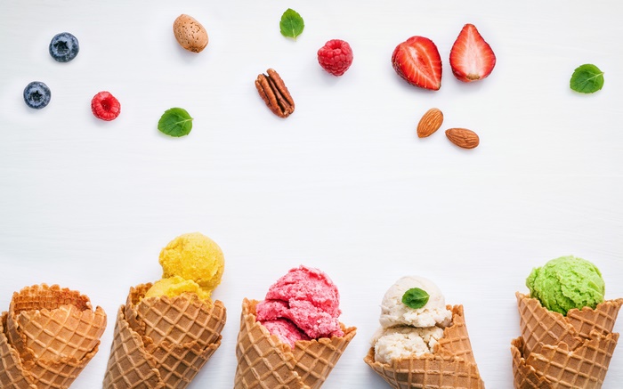 Ice cream cones with berries and nuts on white background