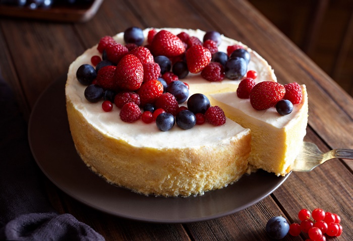 Cheesecake topped with fresh berries on a wooden table