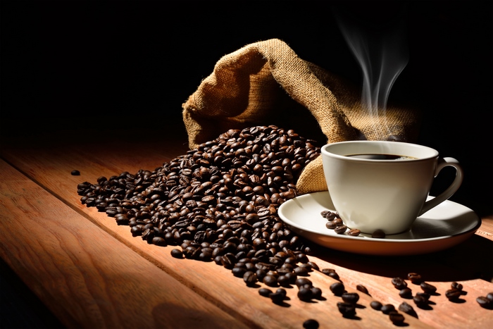 Steaming Cup of Coffee with Coffee Beans on Wood