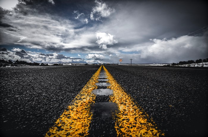 Empty Road with Yellow Line and Cloudy Sky
