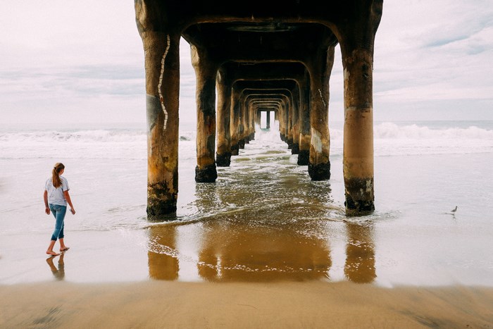 Girl walking under a pier on Manhattan Beach