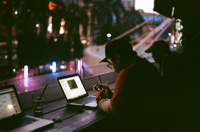 Two people working on laptops at night in Jakarta, Indonesia