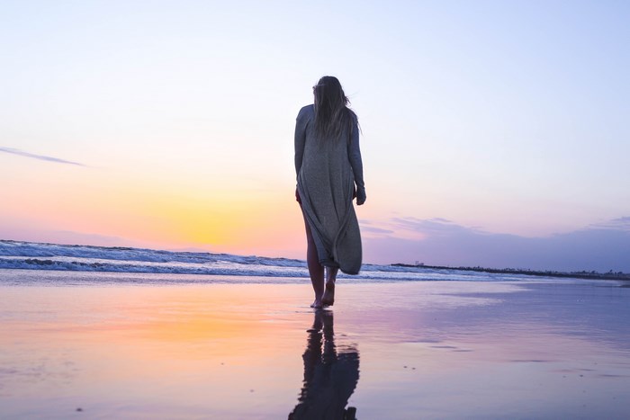 Woman walking on beach at sunset
