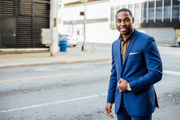 Man in blue suit smiling on a city street