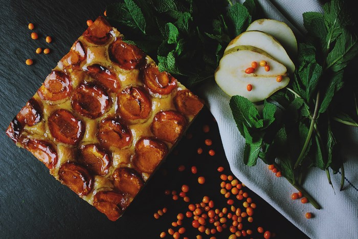 Apricot tart with pears and mint on a dark surface
